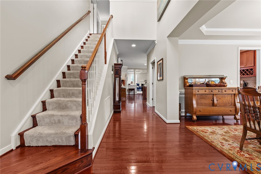 Hardwood flooring, carpeted staircase with wood banister, recessed lighting, and crown molding