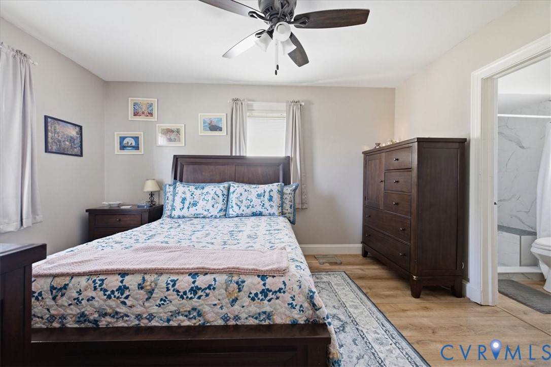LVP flooring, ceiling fan, neutral paint with adjacent bathroom with tiled shower