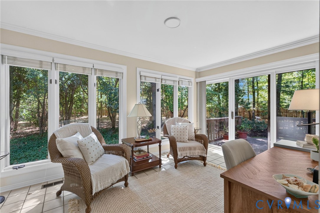 Light-filled sunroom with walls of windows and sliding doors opening to the deck.
