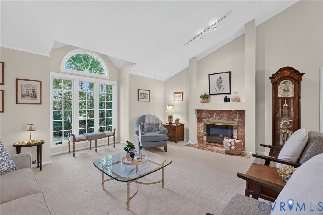 A classic marble fireplace anchors the room, while Palladian-style windows bring in natural light and wooded views.