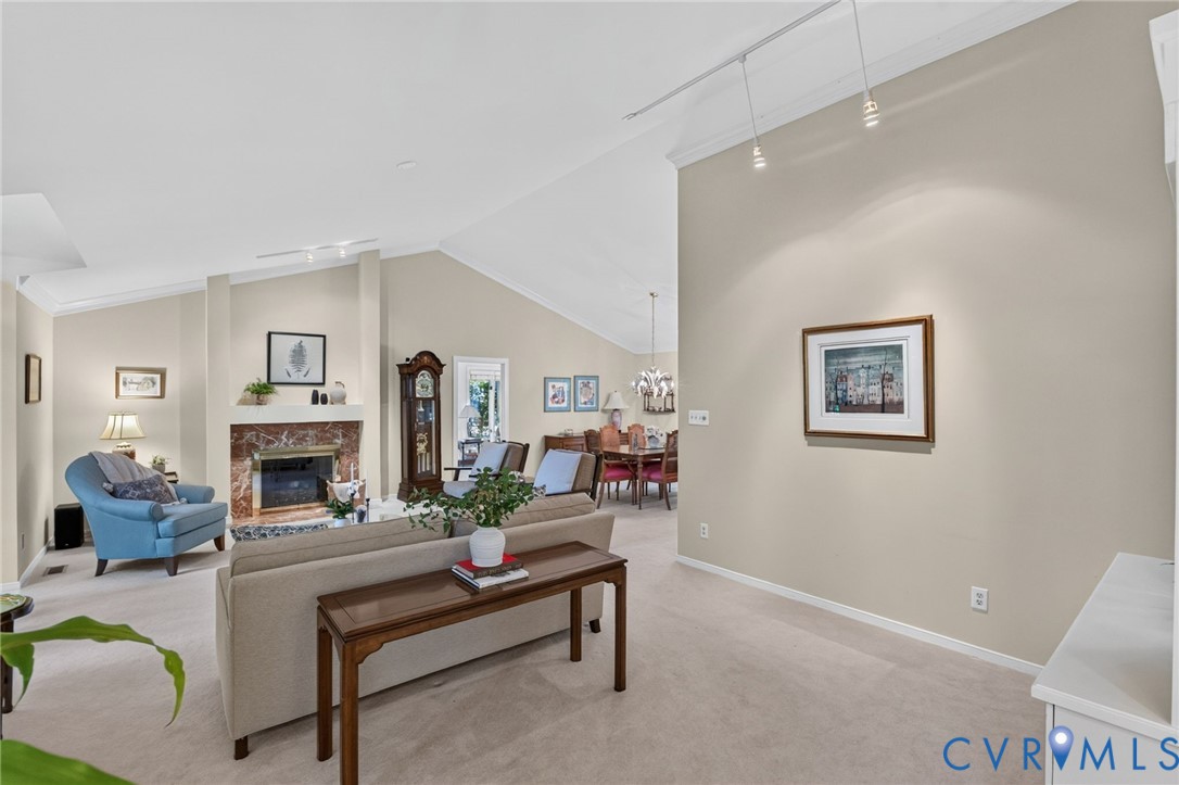 Vaulted and cathedral ceilings give the living room an airy feel, complemented by a classic marble fireplace and abundant natural light.