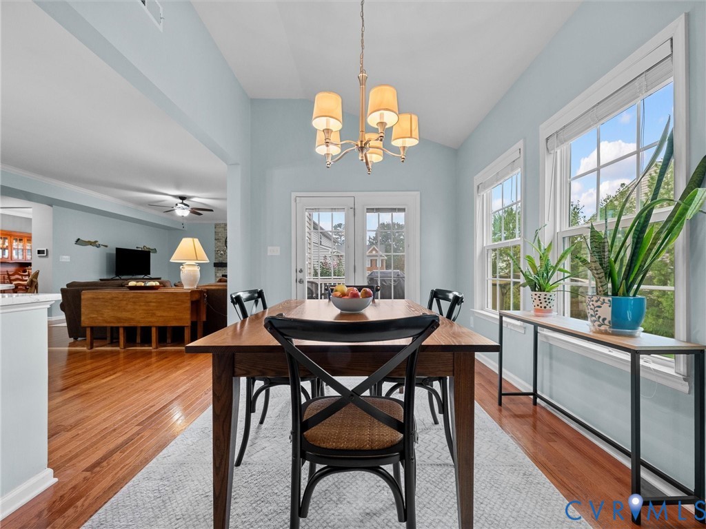 Vaulted ceiling with chandelier, French door, and two large windows with white trim