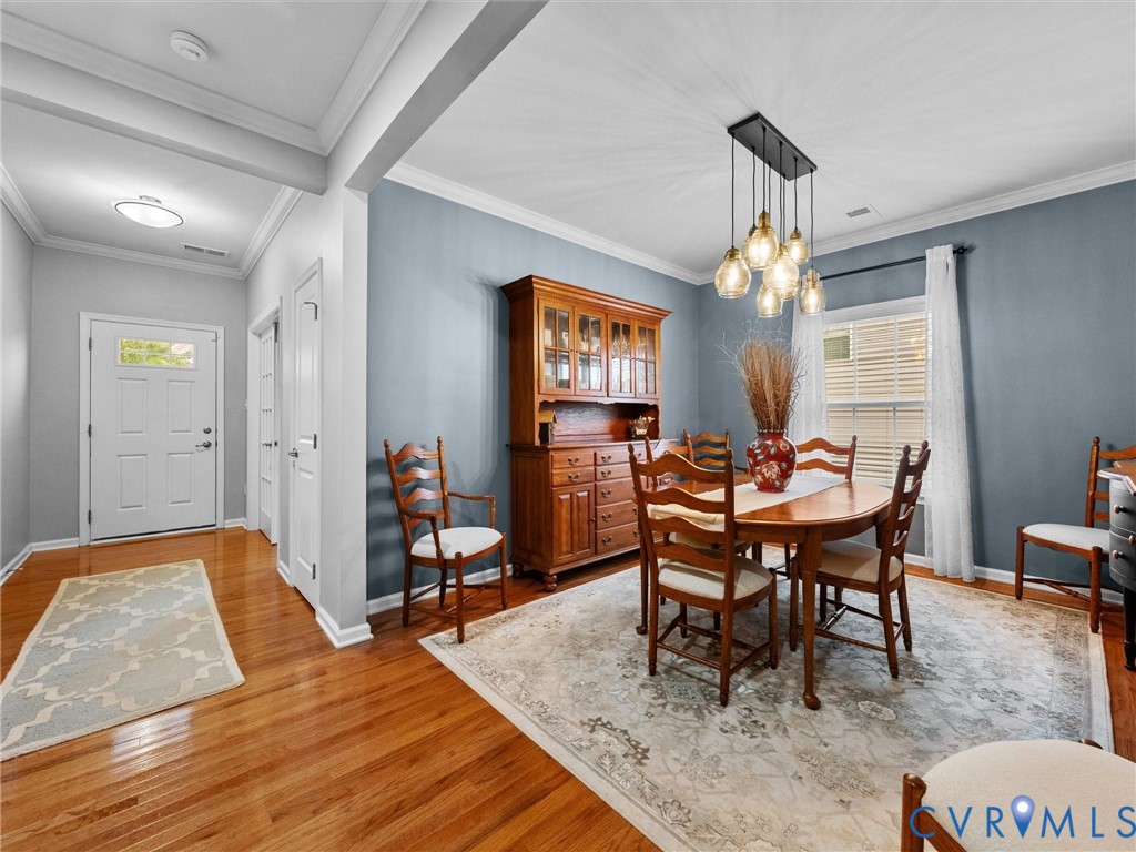 Hardwood flooring, crown molding, modern chandelier, and a transom window at the entry