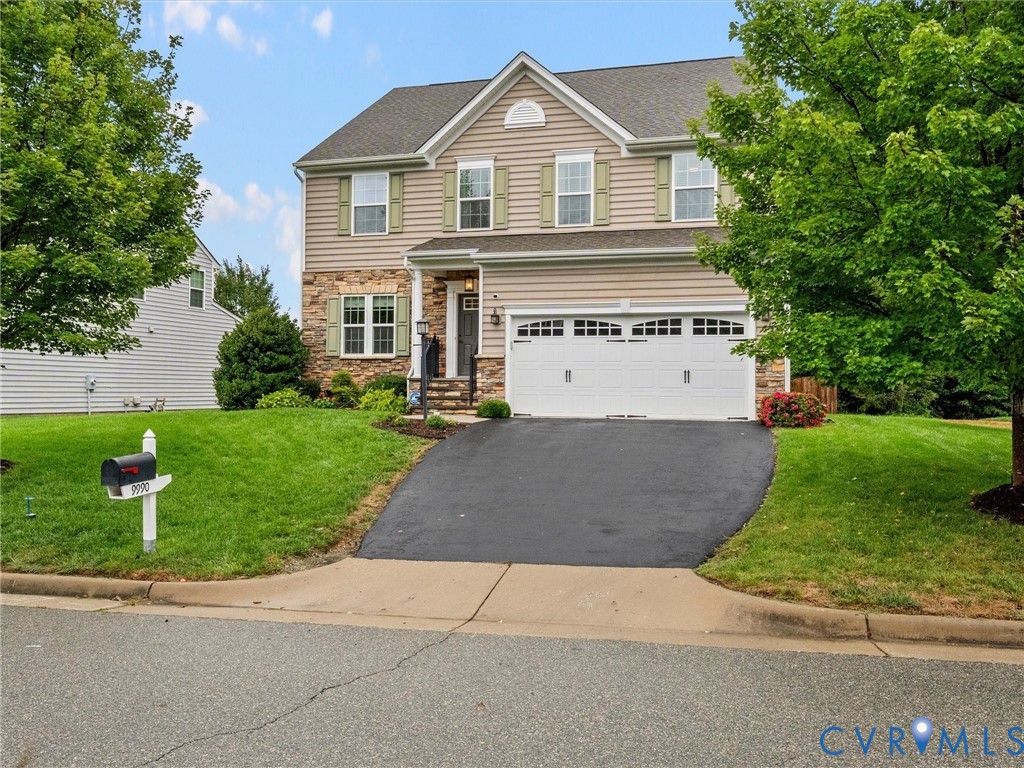 Two-story facade with stone and siding accents, prominent double garage, covered entry, and mature landscaping