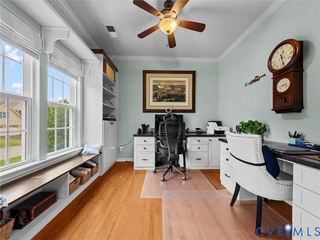 Hardwood flooring, custom built-in cabinetry, window seating, ceiling fan, and crown molding