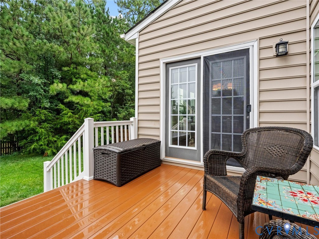 Deck with wood-finish flooring, white railing, and sliding glass door