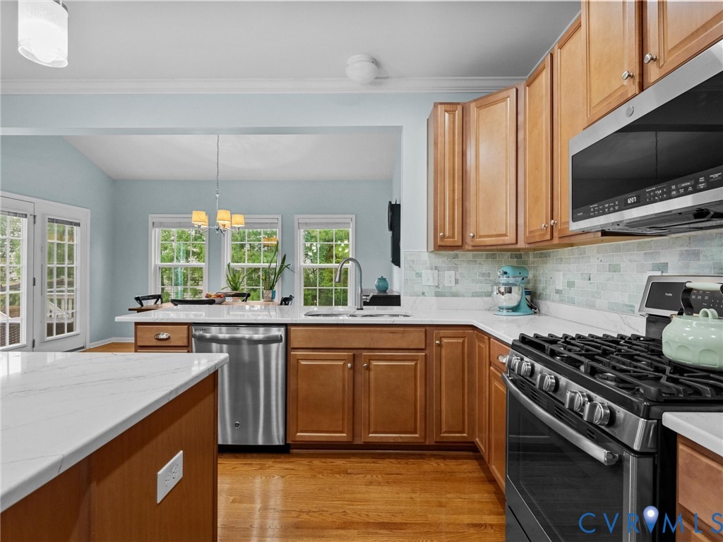 Kitchen featuring wood-finish cabinetry, stainless steel appliances, white countertops, and a subway tile backsplash