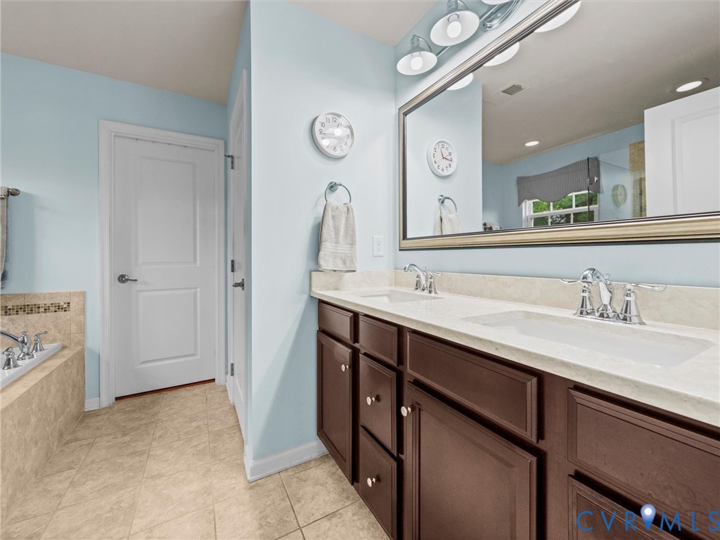 Double vanity with integrated sinks, chrome fixtures, dark wood-finish cabinetry, and a large framed mirror