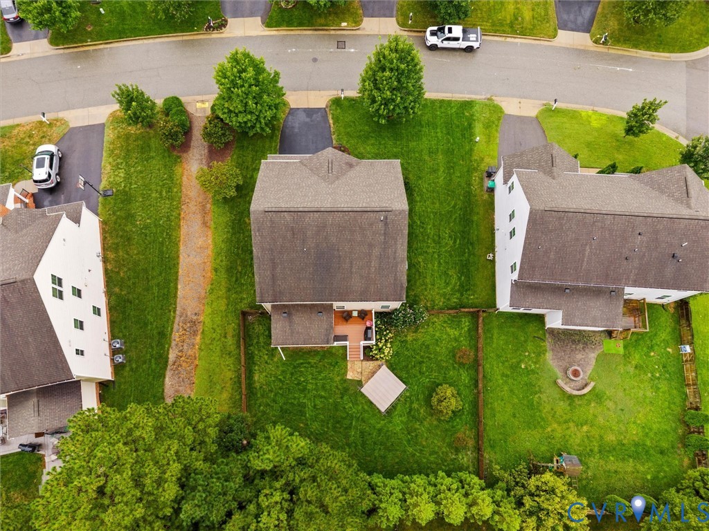 Expansive green spaces and mature trees surround the property, featuring a private fenced yard with a patio and an outdoor fire pit