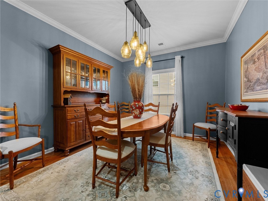 Hardwood flooring, crown molding, a built-in chandelier, and abundant natural light from a window