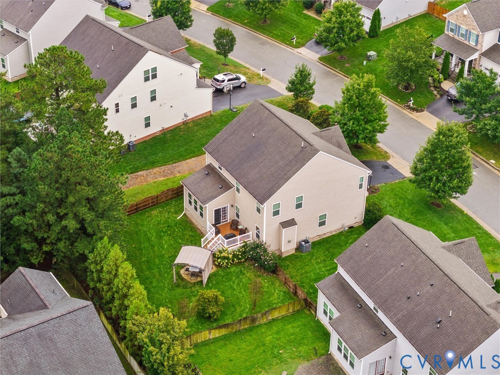 Expansive backyard featuring a manicured lawn, established trees, and a multi-level deck with white railings