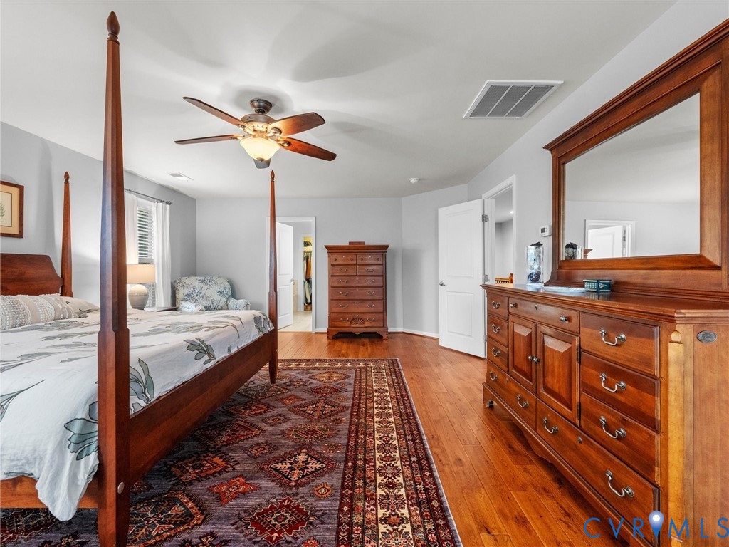 Hardwood flooring throughout, ceiling fan with integrated lighting, and a white interior door