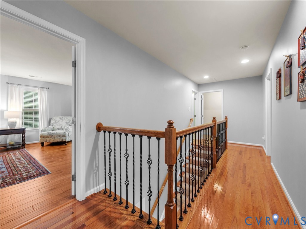 Hardwood flooring throughout, with a wood and wrought iron staircase railing