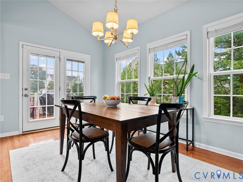 Hardwood-finish flooring, vaulted ceiling, multiple windows, and a chandelier fixture