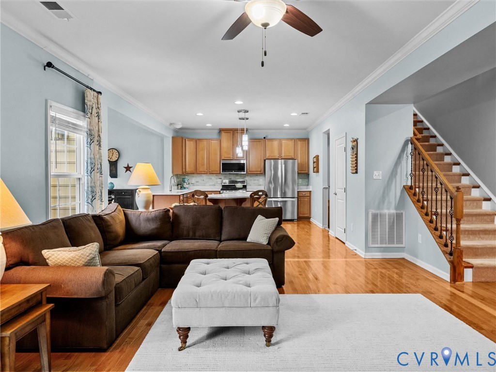 Hardwood flooring, crown molding, ceiling fan, natural wood cabinetry, and stainless steel appliances