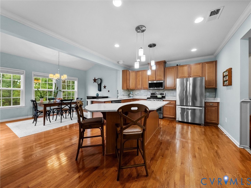 Kitchen featuring wood cabinetry, stainless steel appliances, and a central island with a white countertop