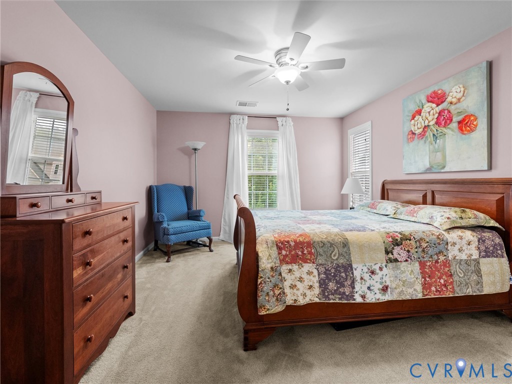 Soft pink walls, window with blinds, overhead ceiling fan, and light-colored carpeting