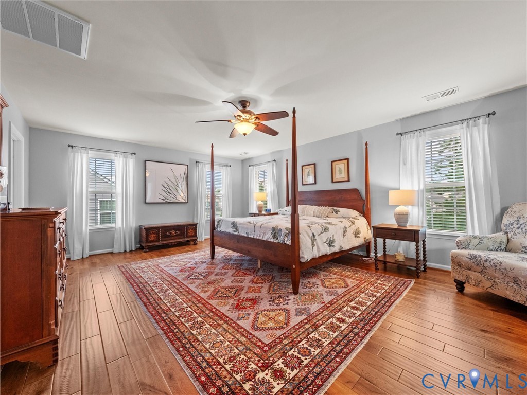 Spacious room featuring wood-finish flooring, light grey wall paint, and multiple windows with white blinds