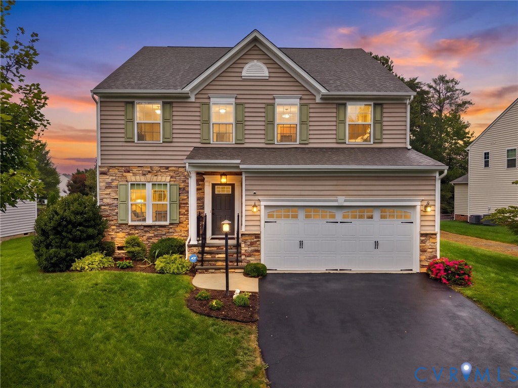 Two-story residence featuring a stone and siding facade, covered entry, attached two-car garage, and established landscaping Two-story residence featuring a stone and siding facade, covered entry, attached two-car garage, and established landscaping