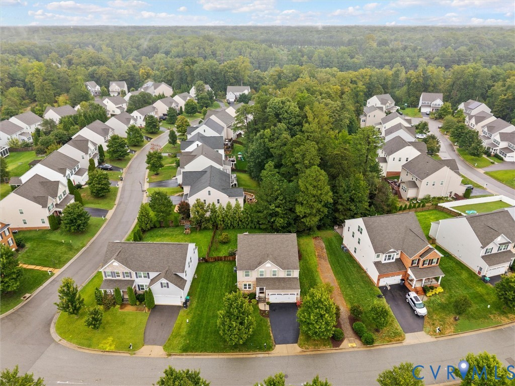 Suburban streetscape featuring detached homes with asphalt driveways, two-car garages, and landscaped front yards
