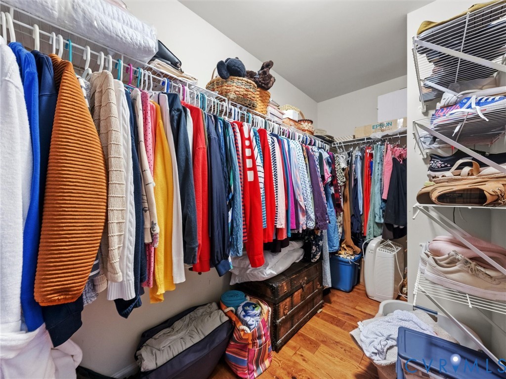 Walk-in closet featuring wood-finish flooring, white wire shelving, and hanging rods