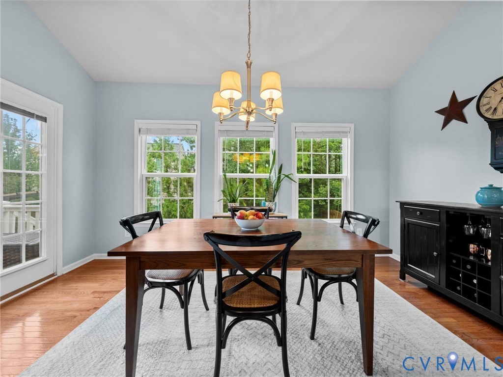 Wood-finish flooring, multiple windows, a chandelier light fixture, and a built-in wine rack with cabinetry