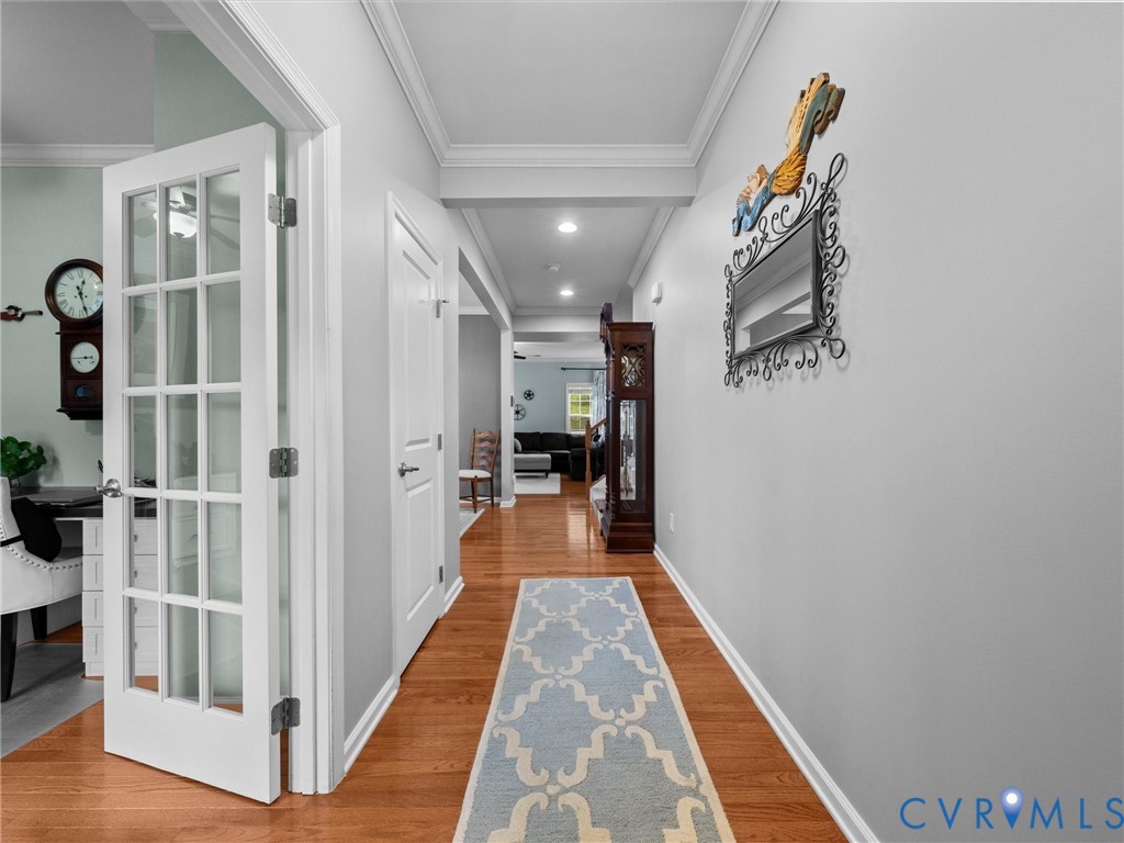 Hardwood-style flooring, French doors, recessed lighting, crown molding, and a built-in storage closet