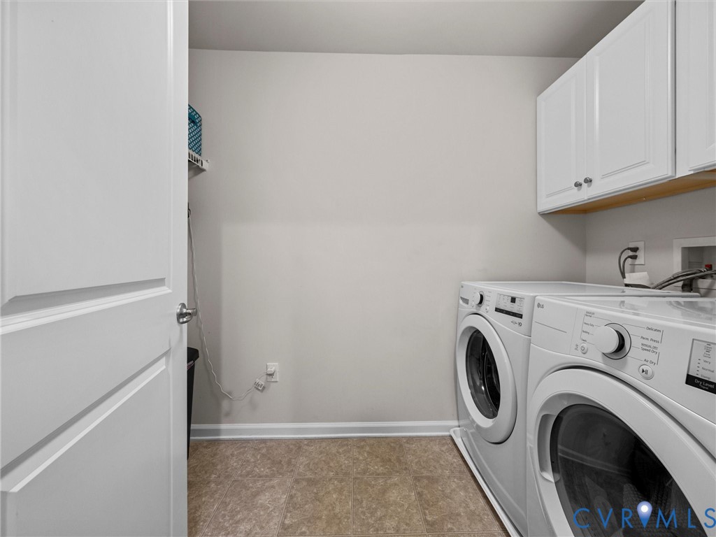 White cabinetry with brushed nickel hardware, light-toned vinyl flooring, and a single wall-mounted shelf
