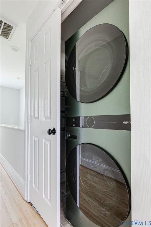Stackable laundry appliances within a dedicated closet, featuring a paneled door with matte black hardware