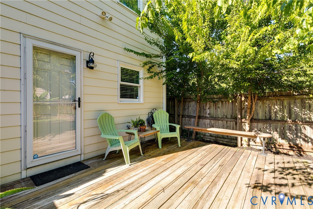 Expansive wooden deck with a privacy fence, mature trees, and exterior lighting