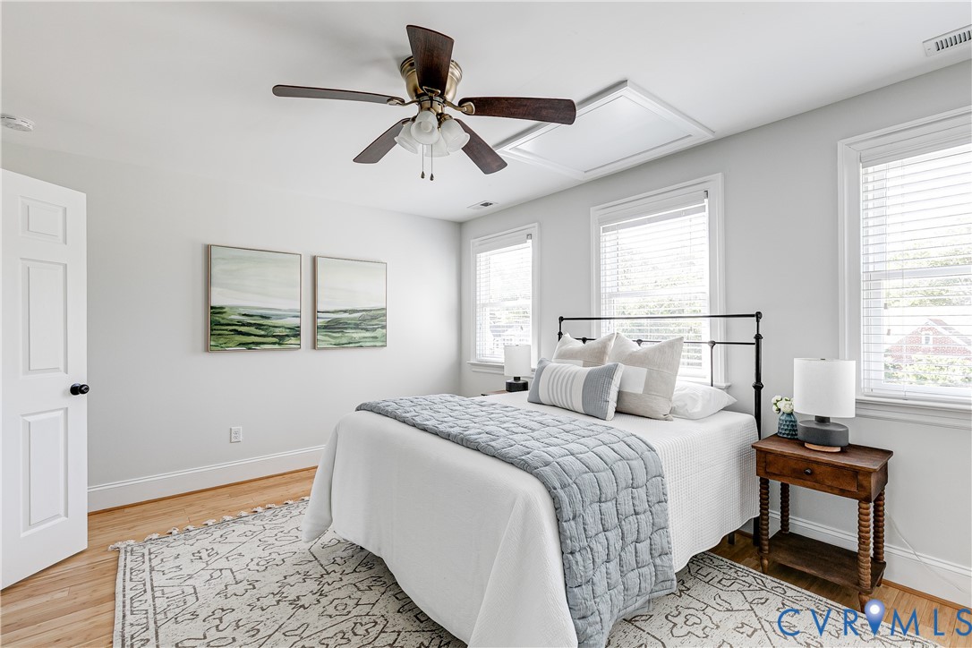 Hardwood flooring, multiple windows with blinds, ceiling fan, solid core door, and an access panel