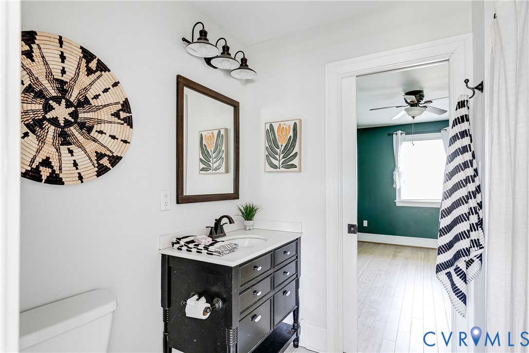Bathroom featuring a dark wood-finish vanity with a white countertop and rectangular sink, complemented by a framed mirror and three-light vanity fixture
