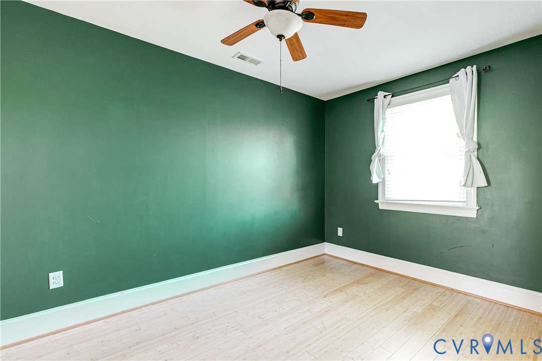 Wood-finish flooring, white window trim, and a ceiling fan with light fixture