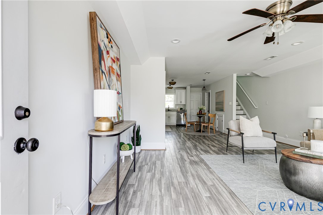 Wood-finish flooring throughout, recessed lighting, ceiling fan, white wall paint, and white staircase with wood-finish handrail