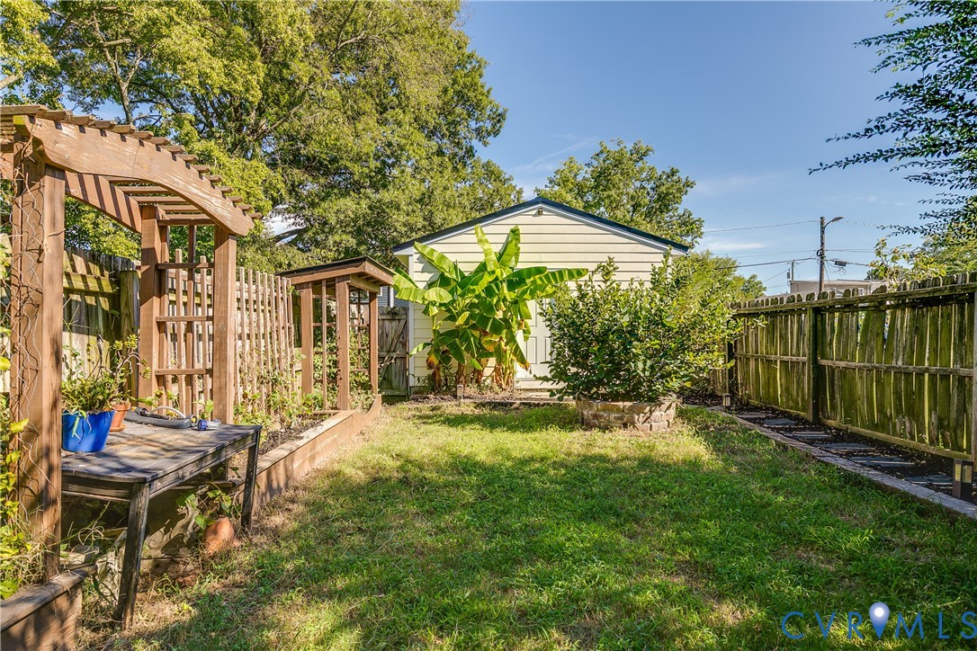 Expansive backyard featuring a wood pergola, raised garden beds, a detached shed, and mature perimeter fencing