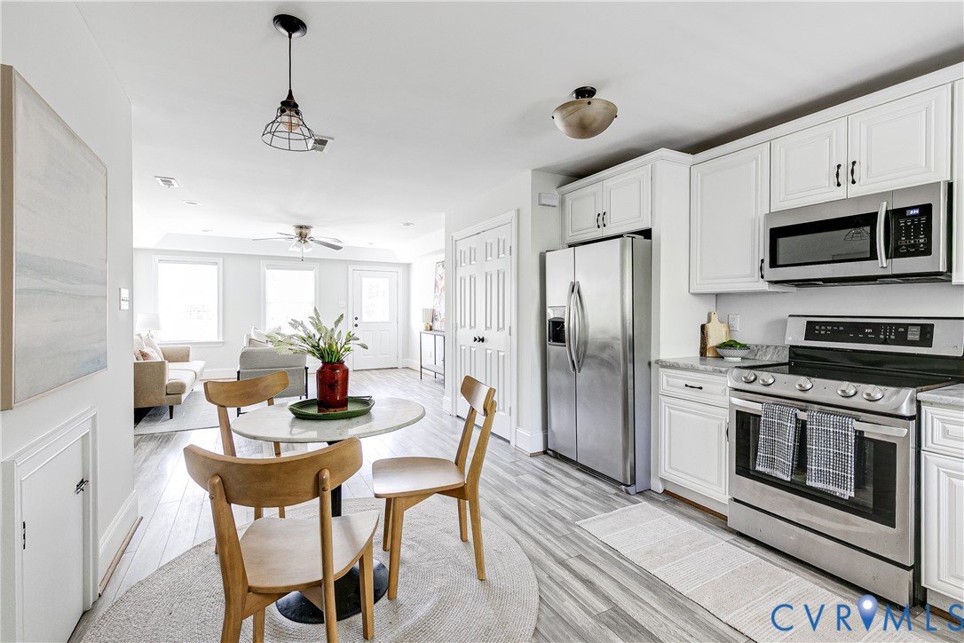 Kitchen featuring stainless steel appliances, white cabinetry, and light-toned countertops