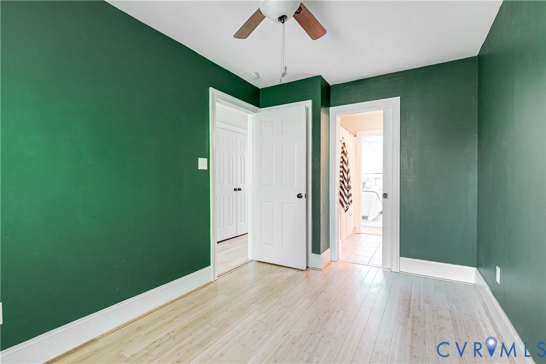 Room featuring wood-finish flooring, a ceiling fan with wood-tone blades, and white trim
