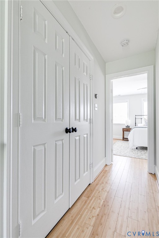 Light wood-finish flooring extending through a hallway with white paneled doors and black hardware