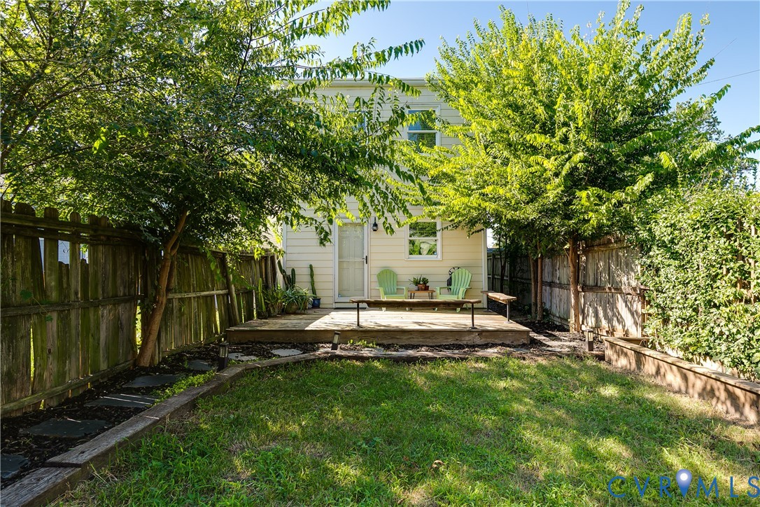 Expansive backyard featuring a wood deck, wood privacy fencing, and mature trees