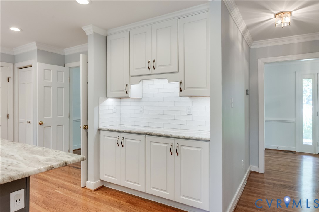 Built-in cabinetry with white shaker-style doors, white subway tile backsplash, and stone countertops