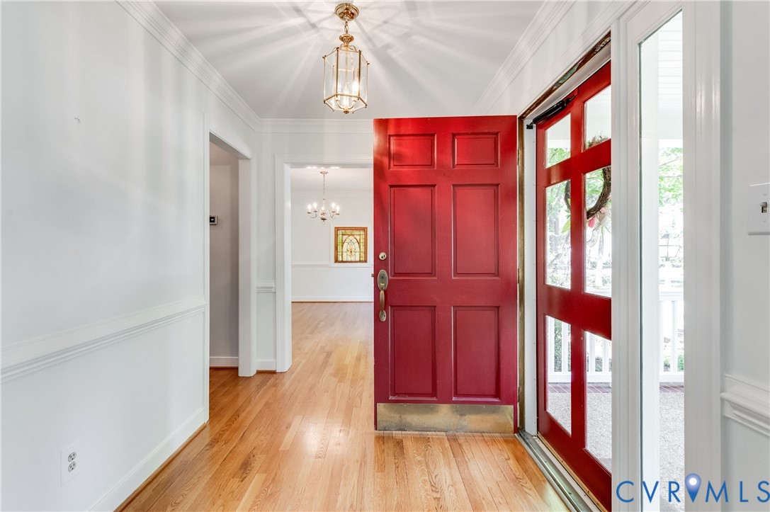 Entryway featuring a red paneled door, wood-finish flooring, and a decorative pendant light Entryway featuring a red paneled door, wood-finish flooring, and a decorative pendant light