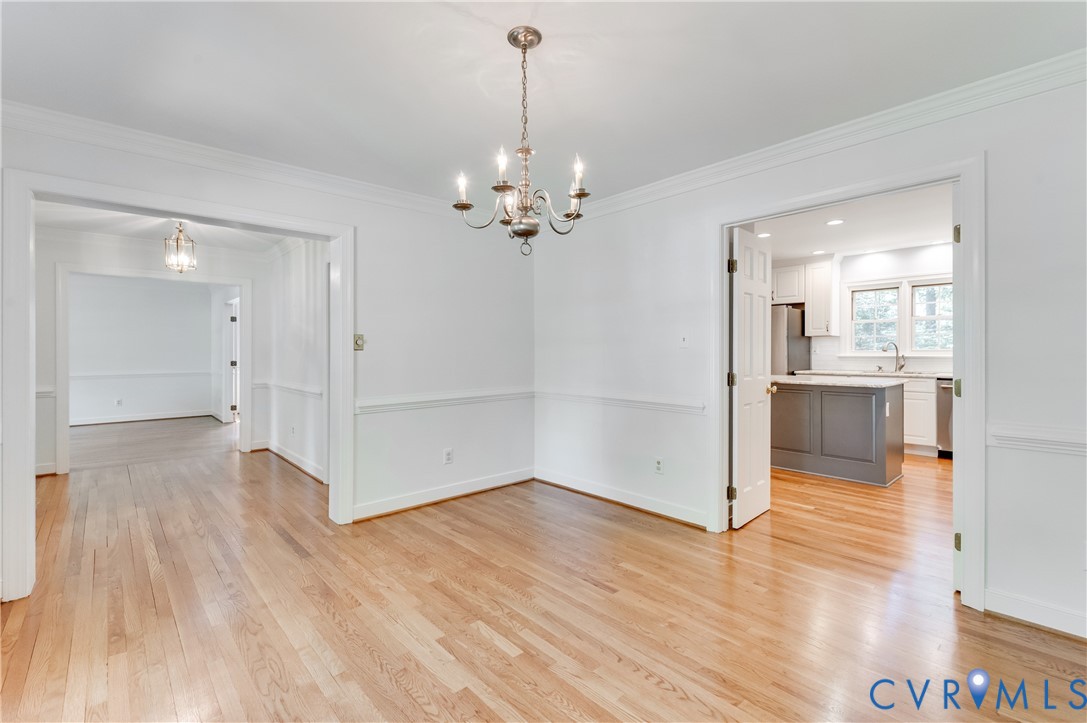 Hardwood flooring throughout, crown molding, chair rail molding, and a chandelier in the dining space