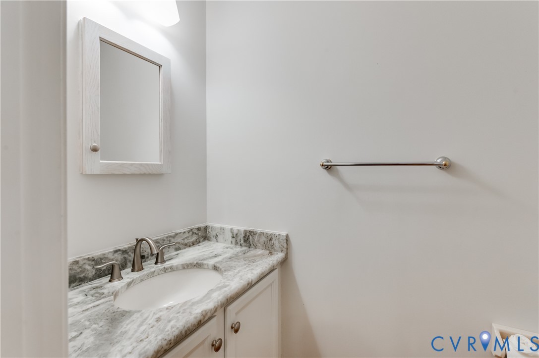 White vanity with a neutral-toned stone countertop, undermount sink, and brushed nickel faucet