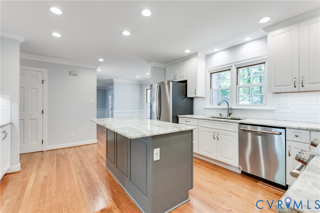 Kitchen featuring hardwood flooring, recessed lighting, white shaker cabinets, and a gray kitchen island with a light-toned countertop