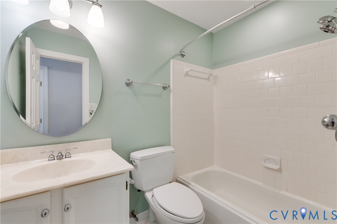 Vanity with integrated sink, chrome hardware, and an oval mirror