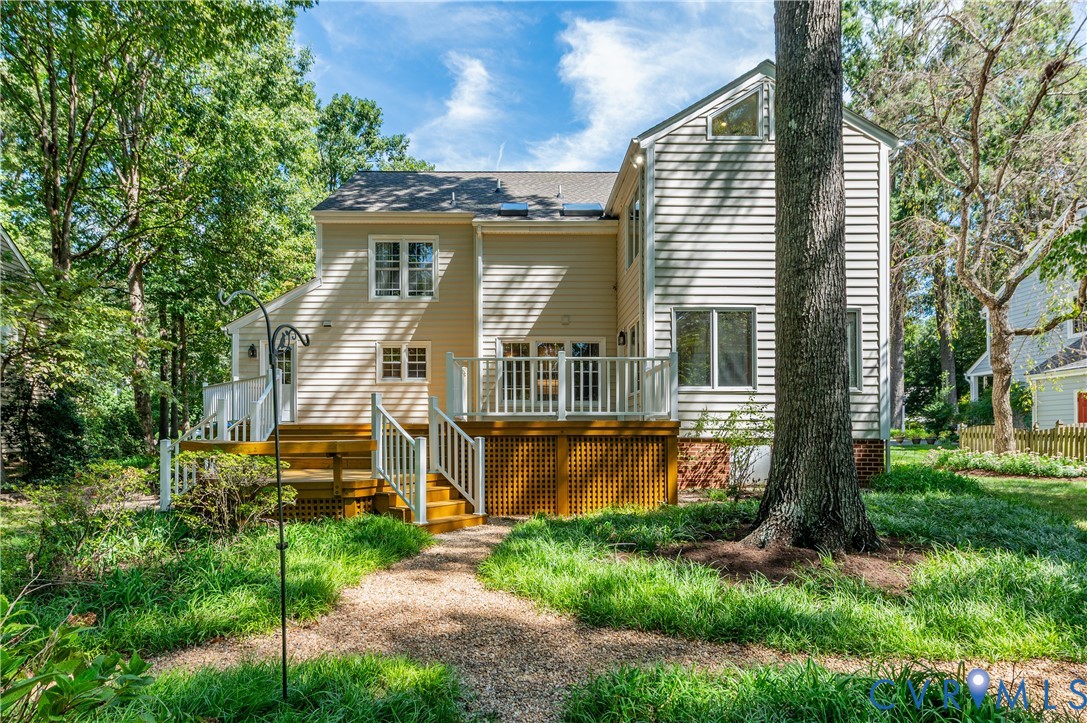 Multi-level deck with white railings, light-colored siding, and a gravel path