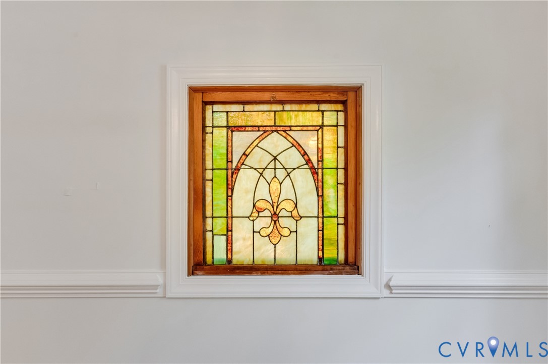 Stained glass window with an arched design and a wooden frame, complemented by decorative crown molding