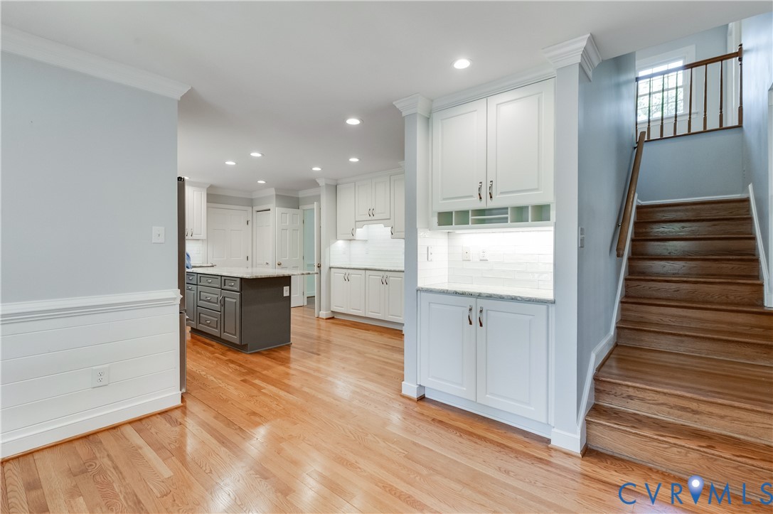Hardwood flooring, built-in cabinetry, staircase with wood treads and railing, and recessed lighting