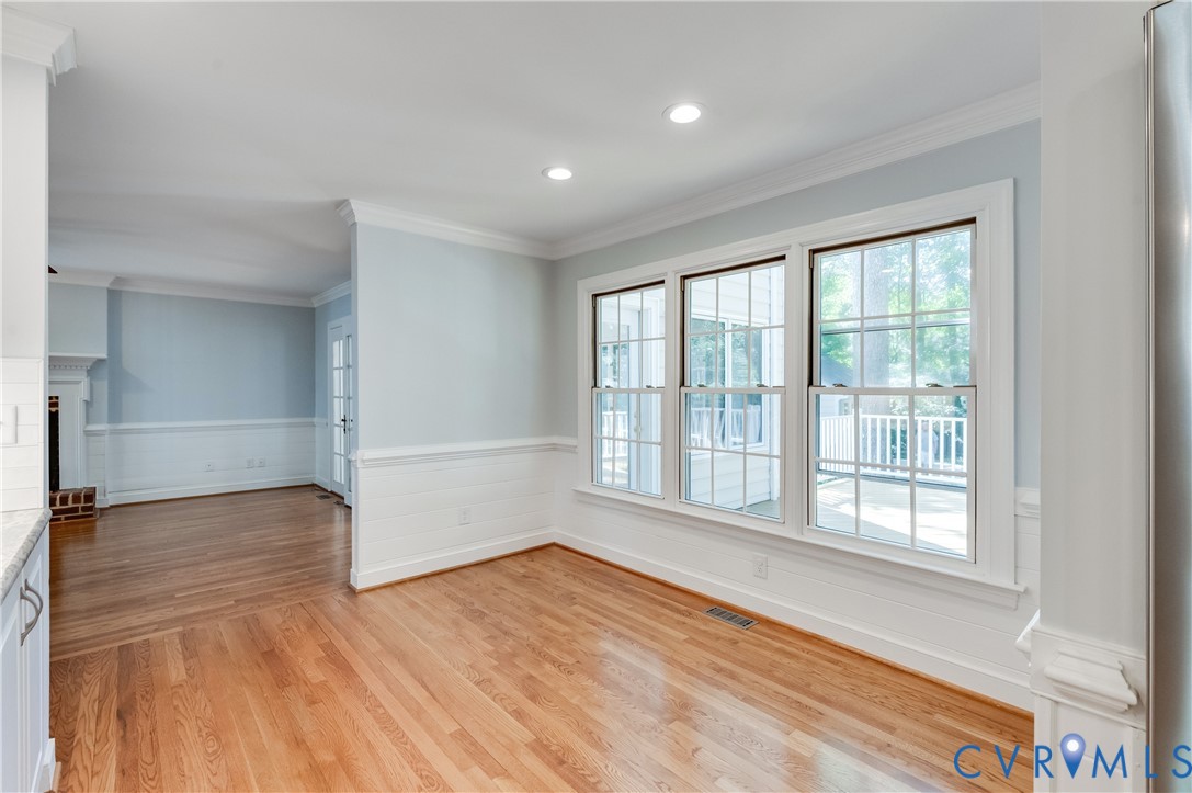 Hardwood flooring throughout, recessed lighting, crown molding, wainscoting, and a wall of windows