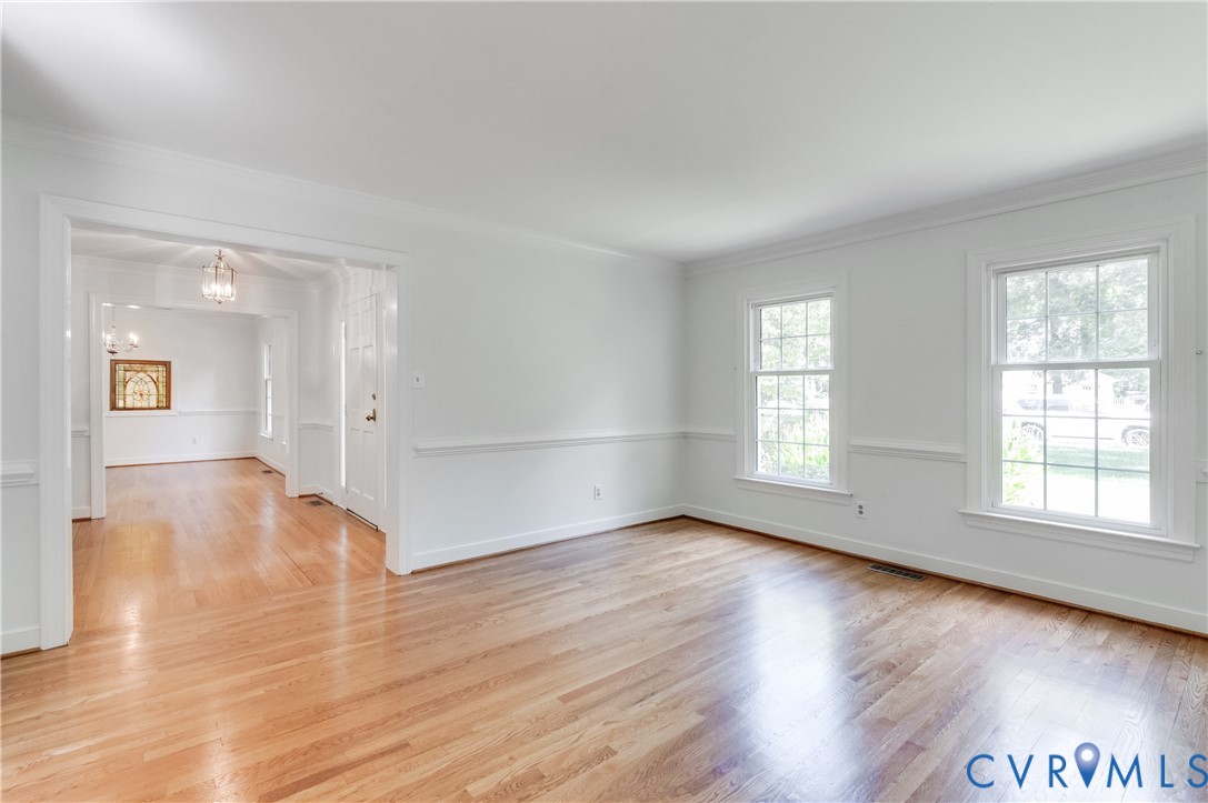 Hardwood flooring, white wall paint, chair rail molding, crown molding, and double-hung windows